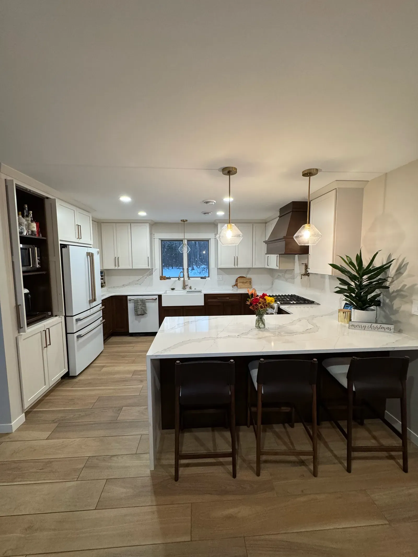 Renovated kitchen with two-tone cabinets, quartz waterfall island, and copper range hood