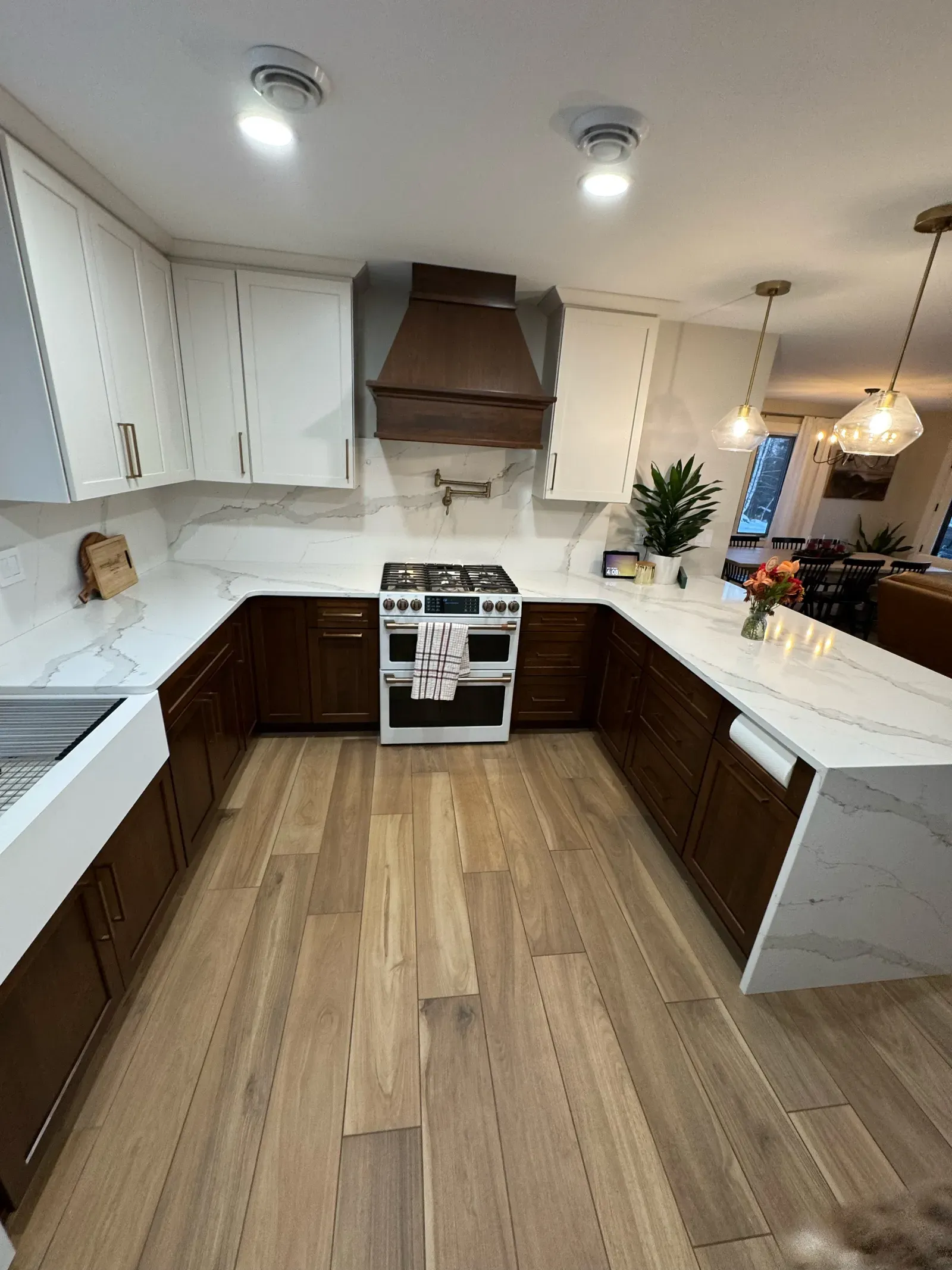 New kitchen from cooking area showing quartz counters, range hood, and pendant lights