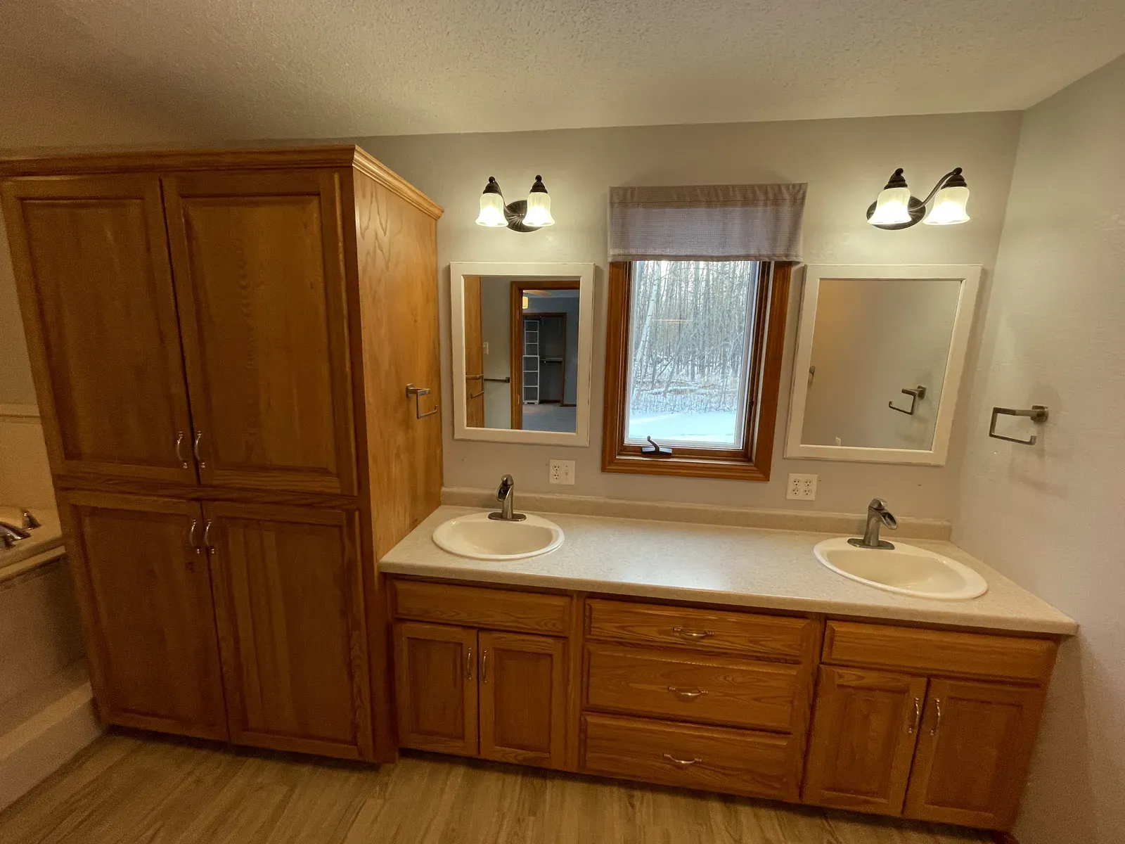 Original double vanity with oak cabinets and dated light fixtures