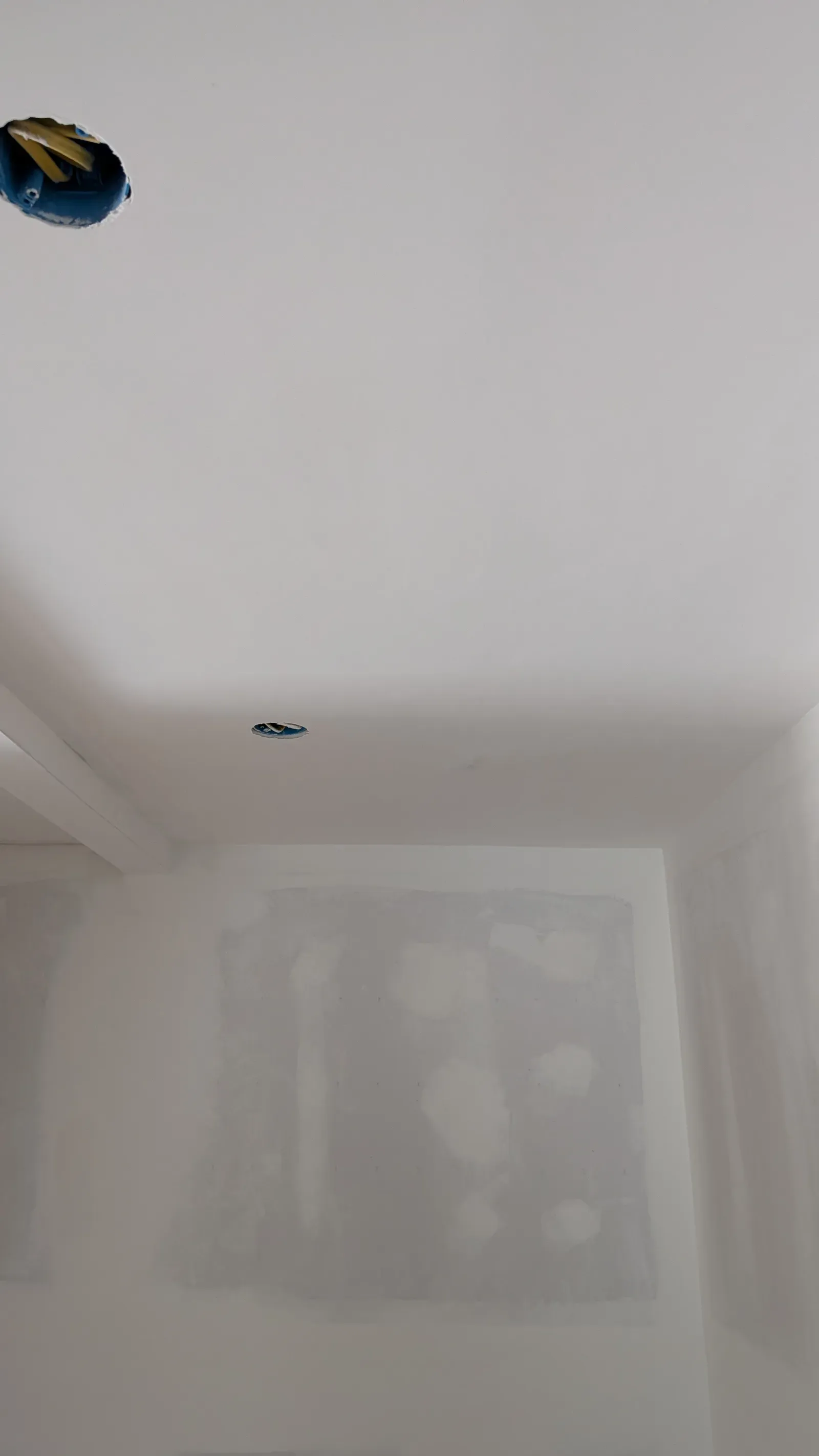 Unfinished drywall showing taped seams and open ceiling fixture boxes